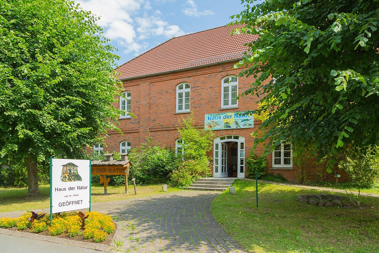 Rotes Backsteingebäude des Museums Haus der Natur in Cismar mit Eingangsschild und blühendem Vorgarten