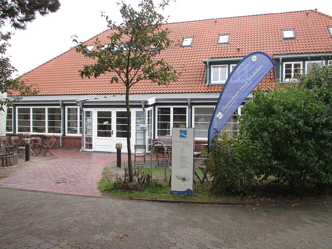 Eingang des Nationalpark-Hauses Wittbülten auf Spiekeroog mit blauer Beachflag und Terrasse