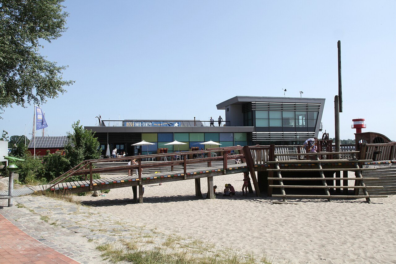 Das Ostsee Info-Center in Eckernförde mit Spielschiff-Anlage im Sand davor