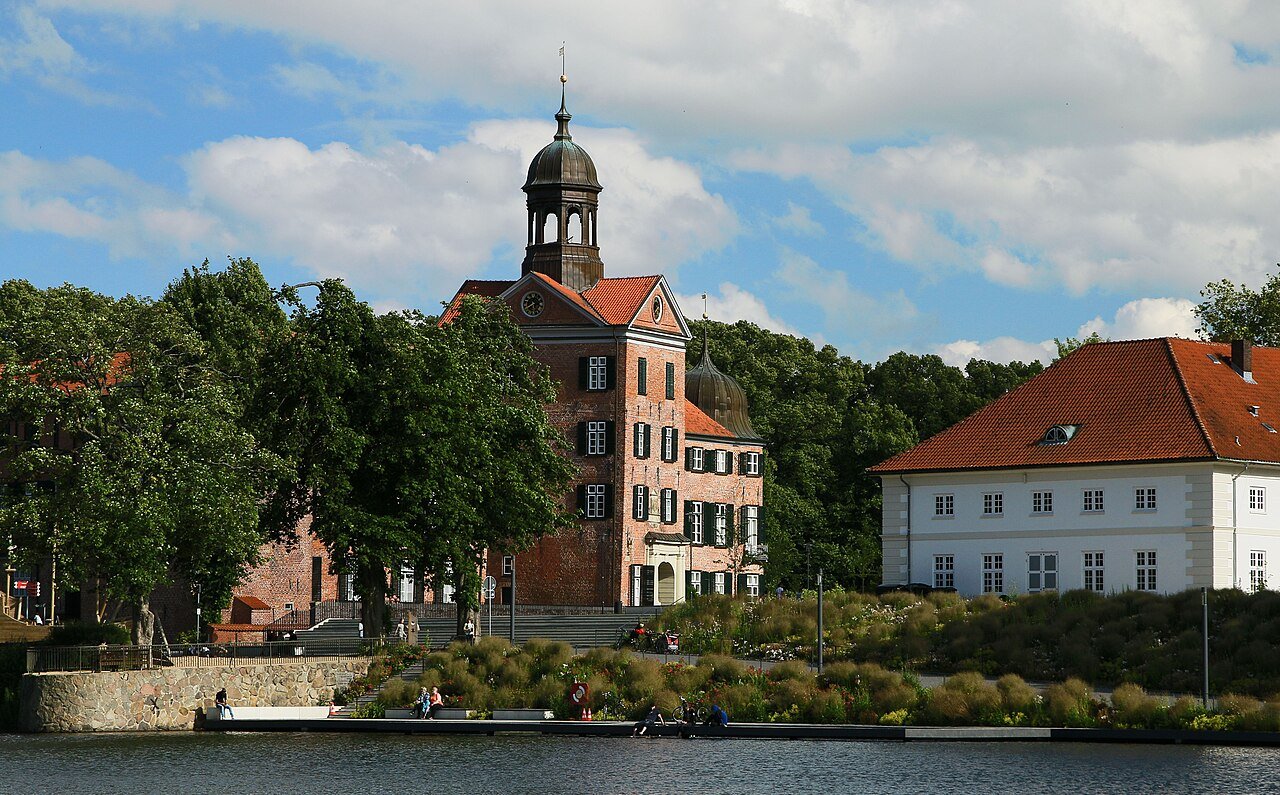 Schloss Eutin mit Glockenturm und Backsteinfassade an der Schlossbucht unter blauem Sommerhimmel