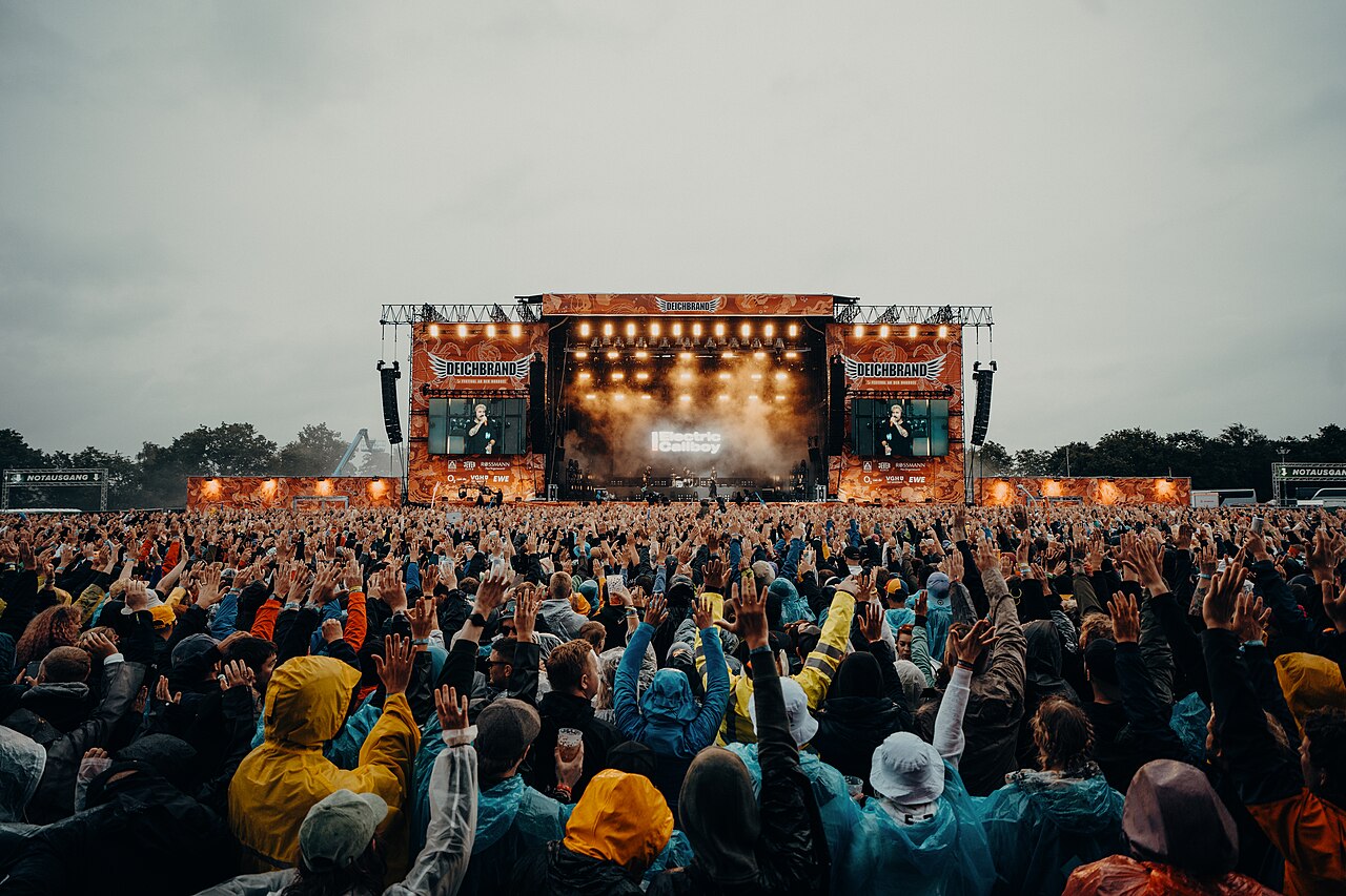 Große Festivalbühne mit Videowänden und dichter Zuschauermenge bei Tageslicht auf dem Deichbrand Festival.