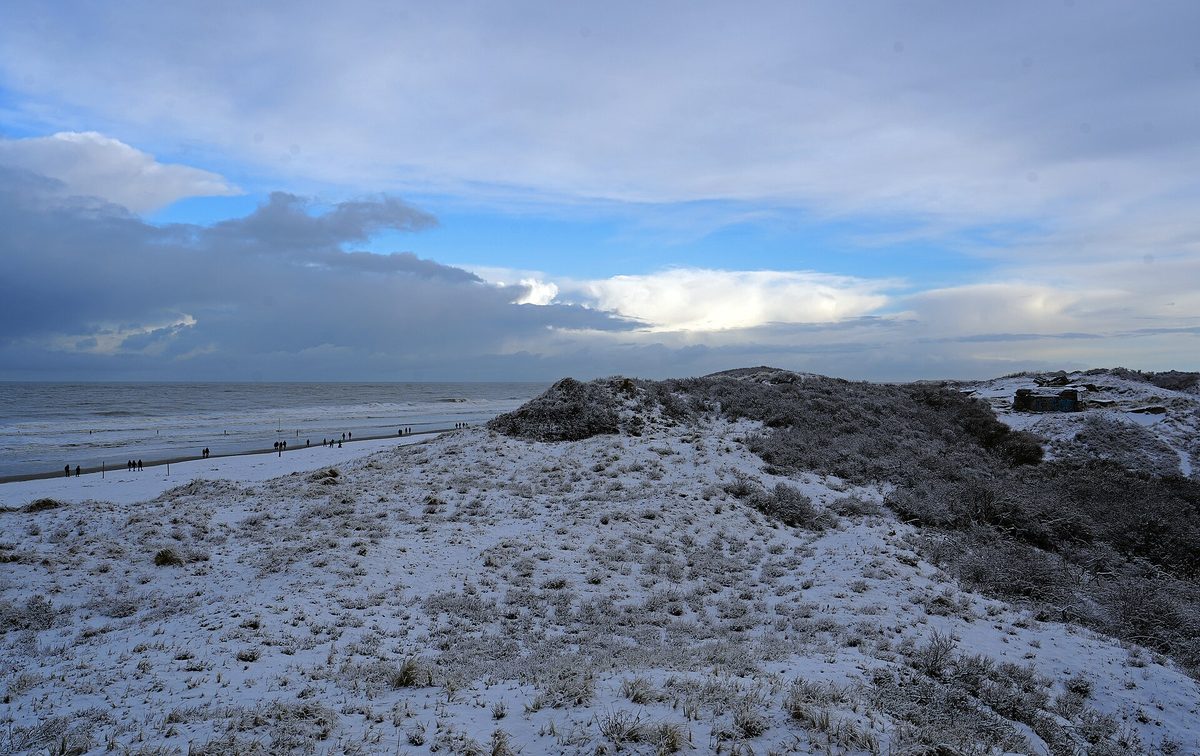 Verschneite Dünen und Strand auf Norderney im Winter.